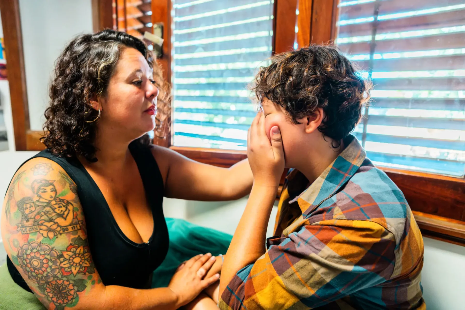 Adult comforting upset person by window