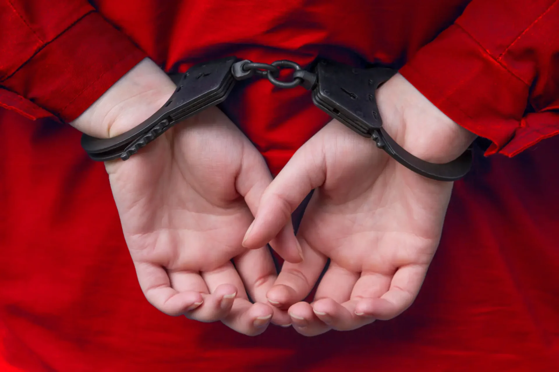 Hands cuffed behind back in red clothing